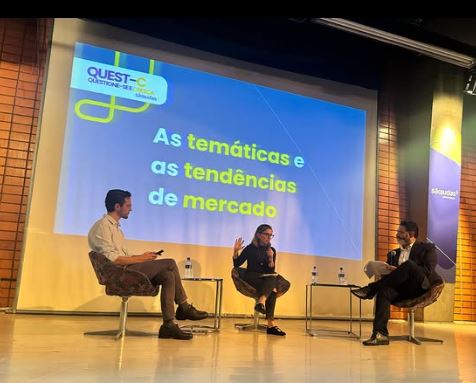 Julio Araujo mediando painel com três convidados em evento da Quest-C